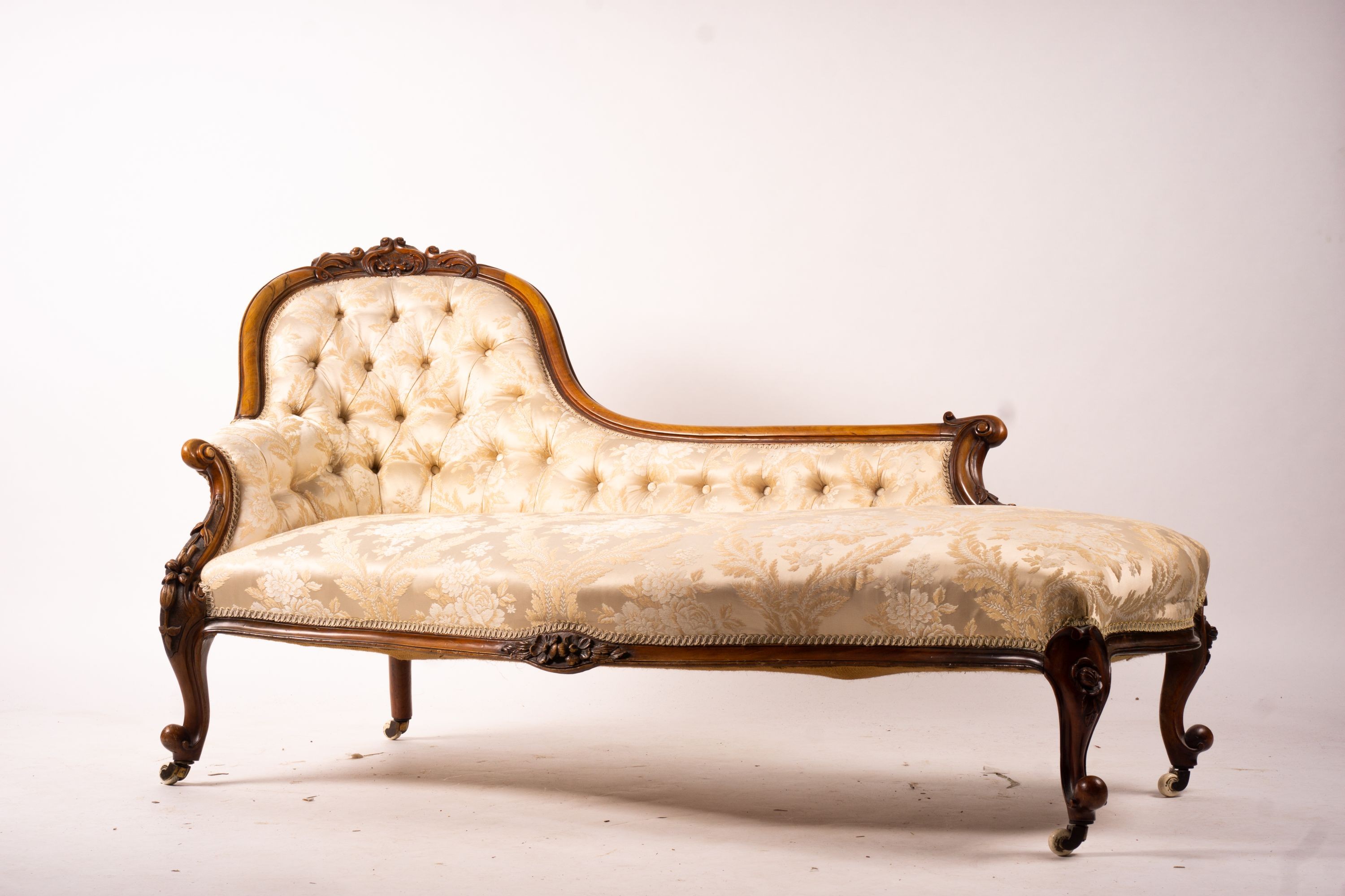 A late Victorian carved walnut three piece salon suite, comprising chaise longue, open armchair and nursing chair